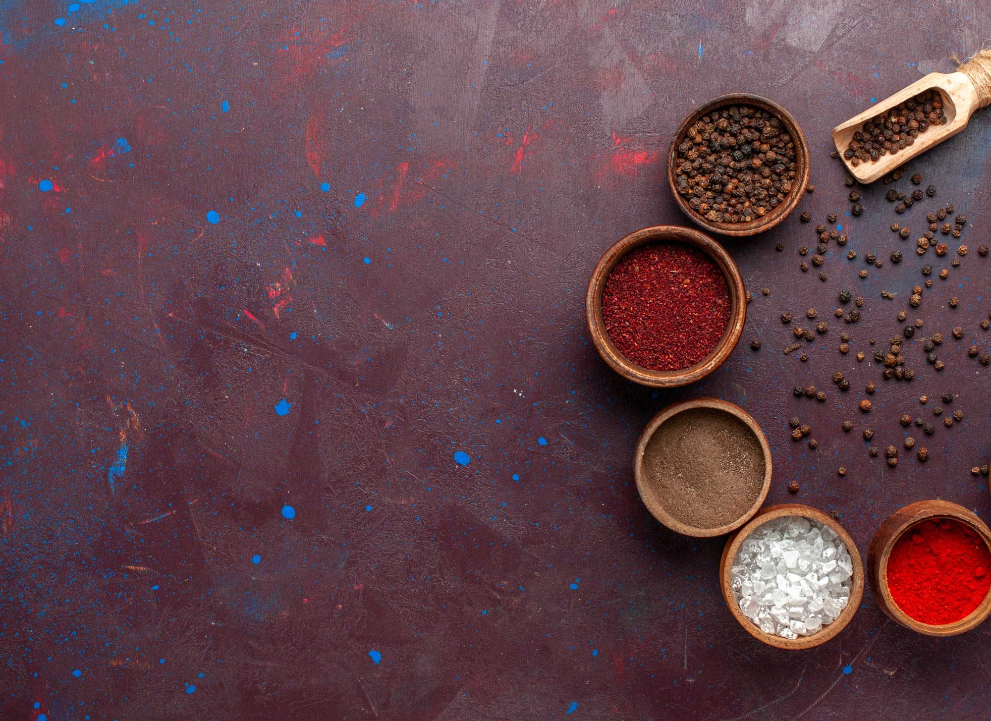 Spices in bowls on a colourful textured surface